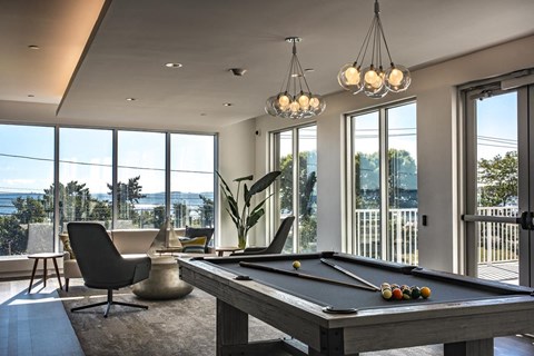 a pool table in a living room with large windows